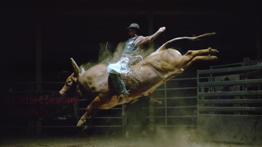A man is riding a bull as others watch
