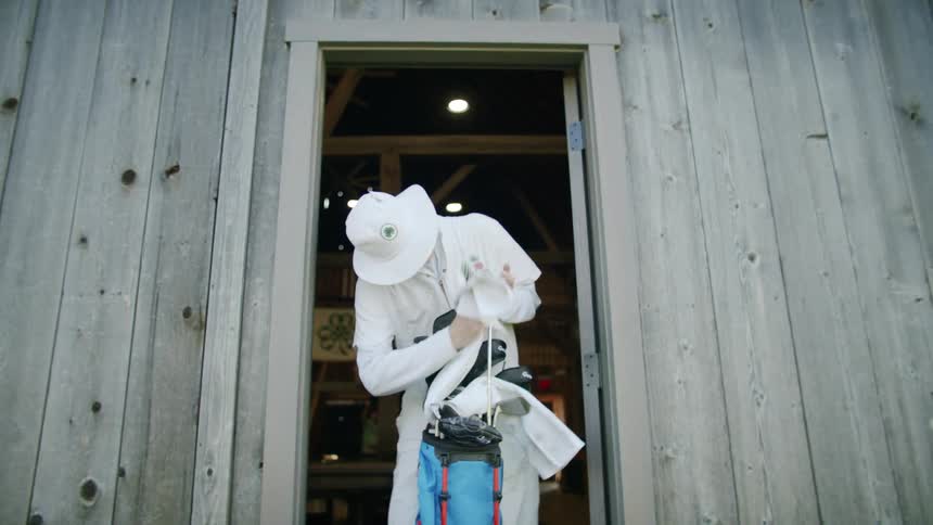 Man stands in doorway with golf bag and wipes golf club