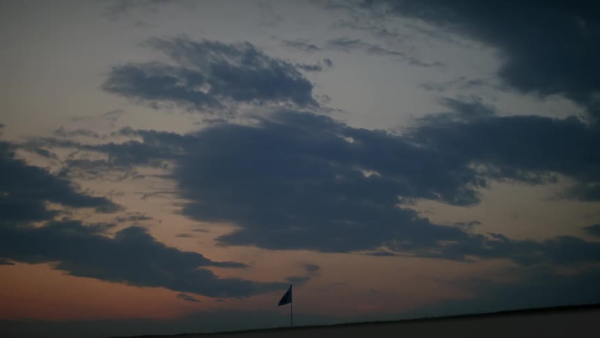 Silhouette of a solitary flag waving in the wind at dusk