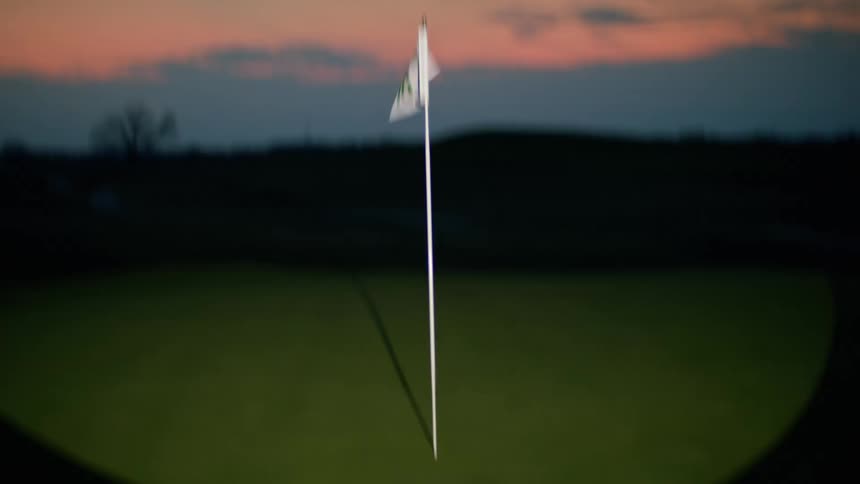 A white flag waving on the golf course at sunset