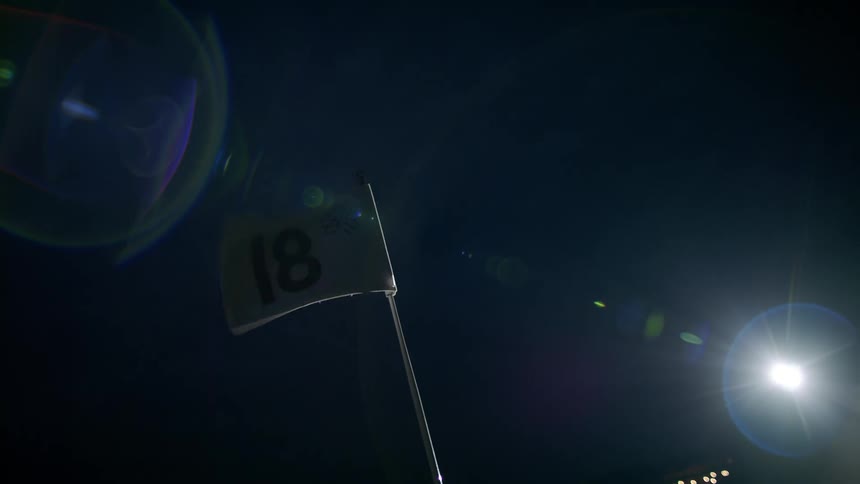 Eighteenth hole flag waves against night sky