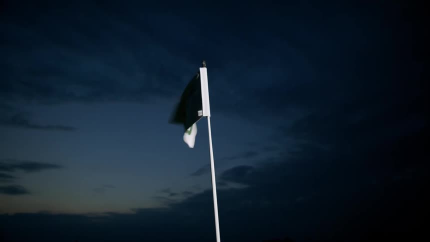 Eighteenth hole flag flaps in the dark on golf course