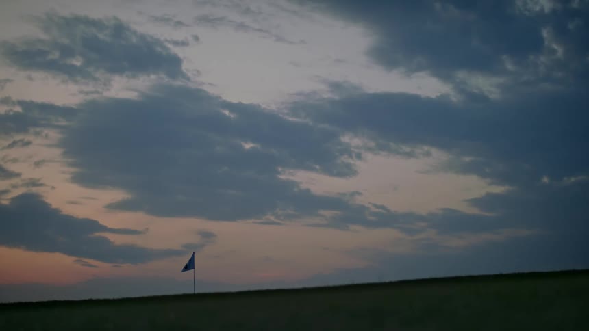 Small flag on a grass field at sunrise