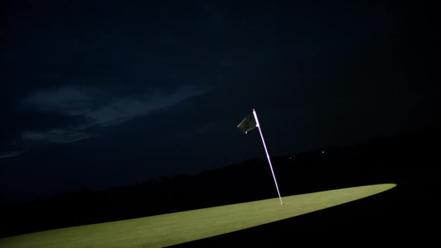 A white flag illuminated by a beam of light waving against the wind