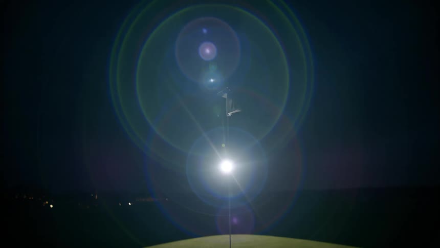 A flag waving on the golf course at night