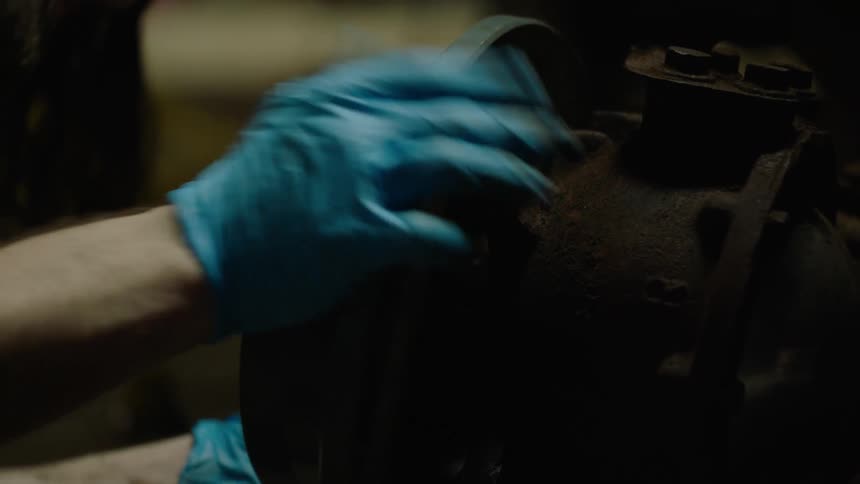 A man wearing gloves picks up a round collar part and attaches it to a pipe