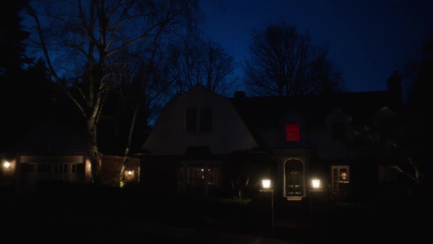 Lights glow outside of houses in a neighborhood at night