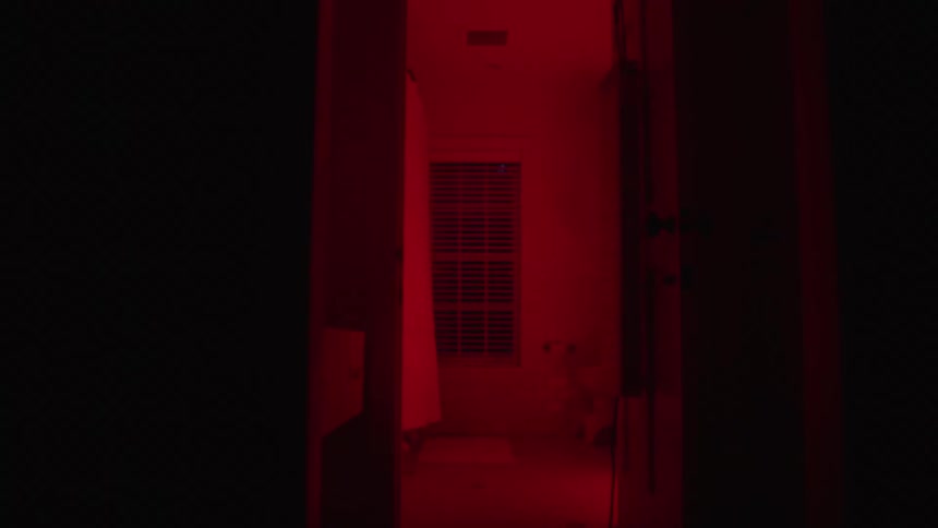 Dark corridor leading to a red lit room