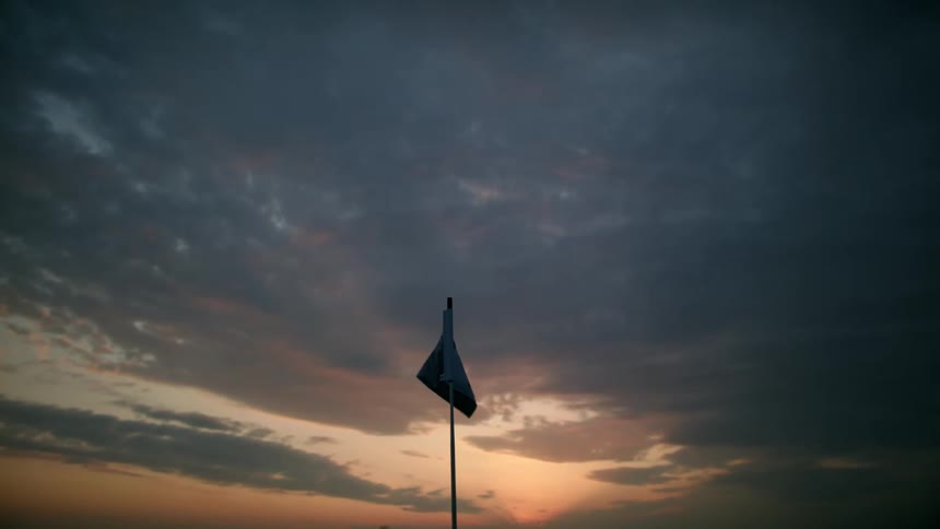A white flag waving in the wind at sunset