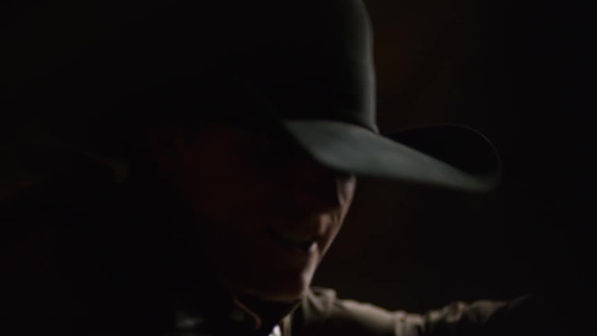 A man is wearing a cowboy hat in the dark