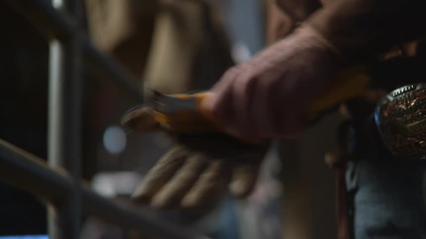 A man rubs his glove with a tool and pulls a rope