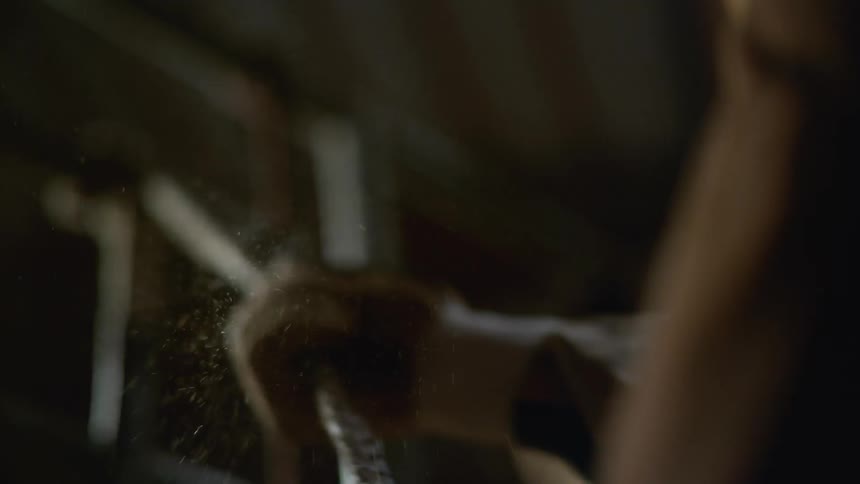 A gloved hand pulls on a rope causing dust to fly