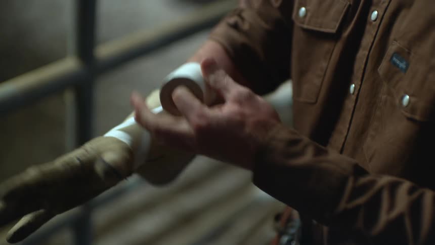 A man puts on a glove and tapes it on