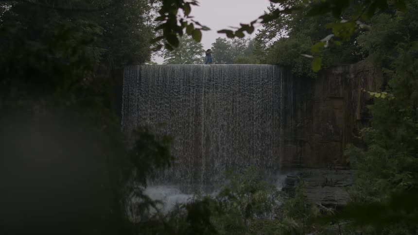 Couple hug over a waterfall in the mountains at evening
