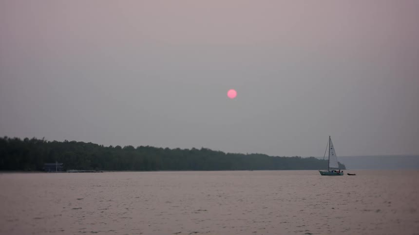 Sailboat at sea next to the coast during dusk or dawn