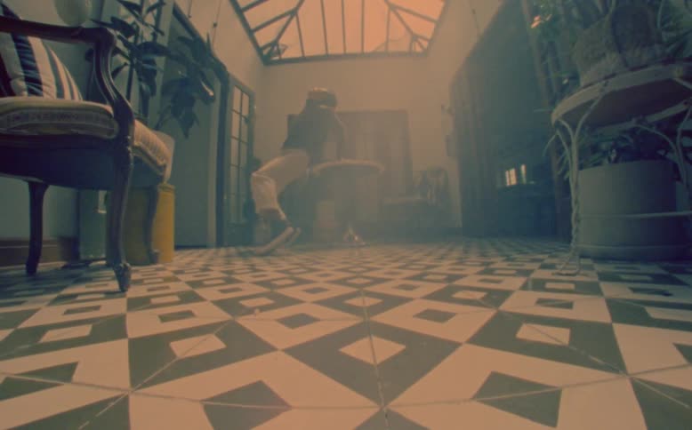 An asian man doing a dance performance in a room where he throws himself on the floor