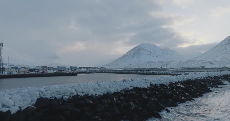 Small village by the lakeside and sea with a backdrop of snowcovered mountain range