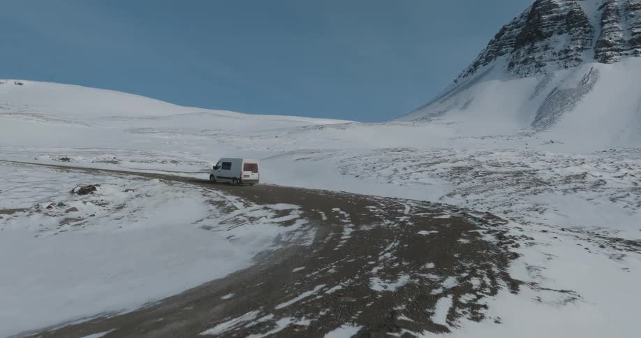 Aerial of a vehicle climbing a mountain road at winter