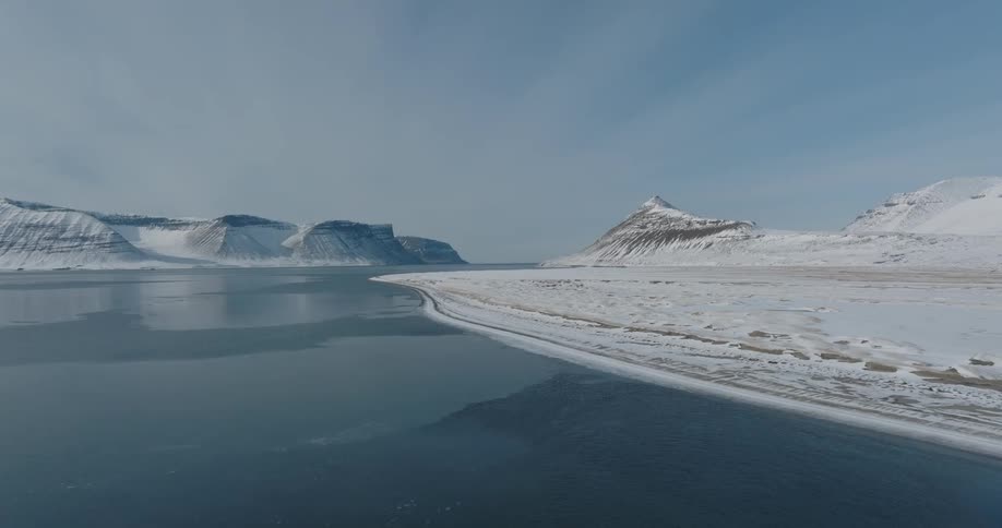 An aerial view of a lake on a snowcovered mountain shore