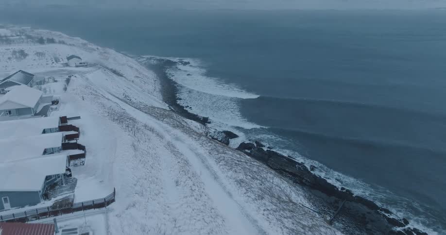 Waves wash against the shores of a snow covered coastal area