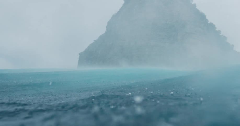 Waves and splashes as rain falls near a small island