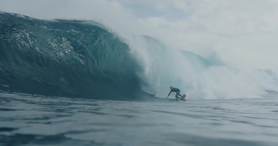 Man catching a massive wave and surfing inside of it