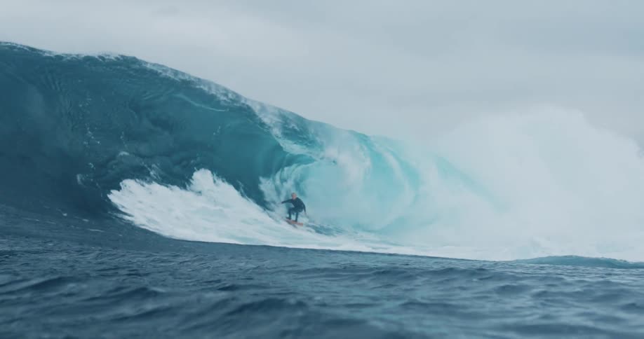 Man surfing and getting barreled by a huge wave