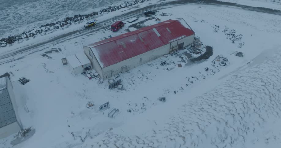 A coastal factory and warehouse covered in snow