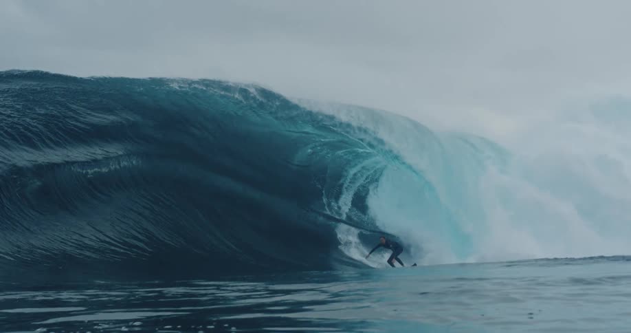 A man surfs an orange surfboard on a cloudy day