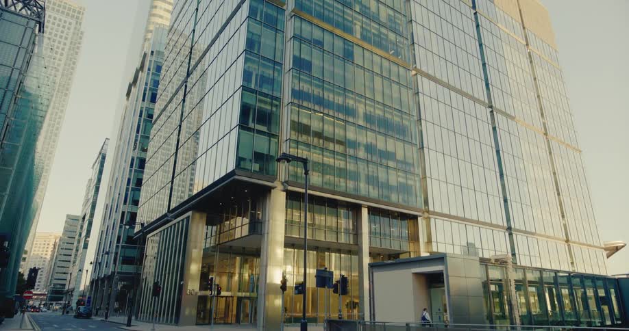 A man walks on a downtown sidewalk near tall buildings with many windows