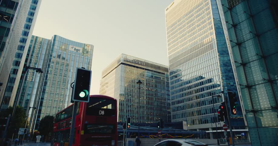 Red double decker bus passes city buildings