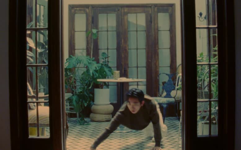 A man jumps from a chair and throws himself on the floor in dance performance movements in an environment with a chair and table