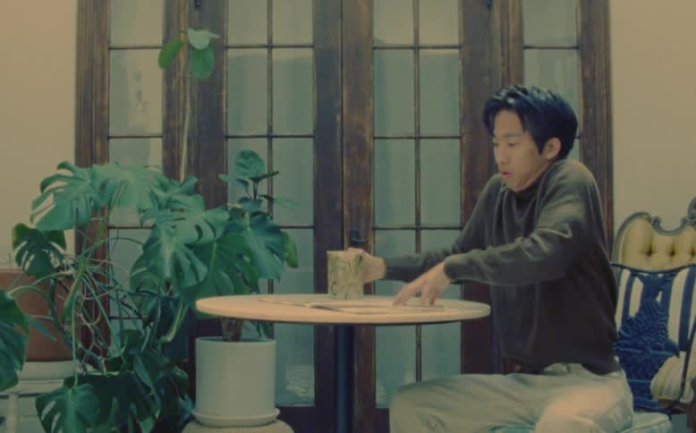 A man drinking from a mug starts to shake until he turns the page of the magazine he is reading