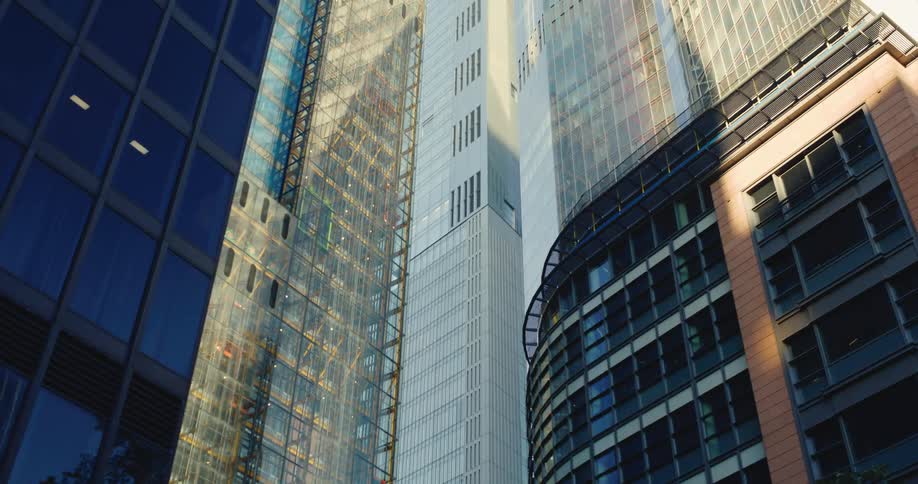 The sun shines upon tall downtown skyscrapers with unique architecture