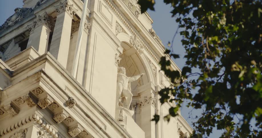 A white building with classical architecture and statues at the top