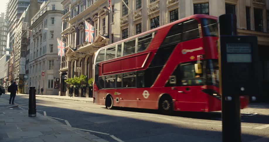 View of a street with people walking buses passing by and the architecture of tall buildings