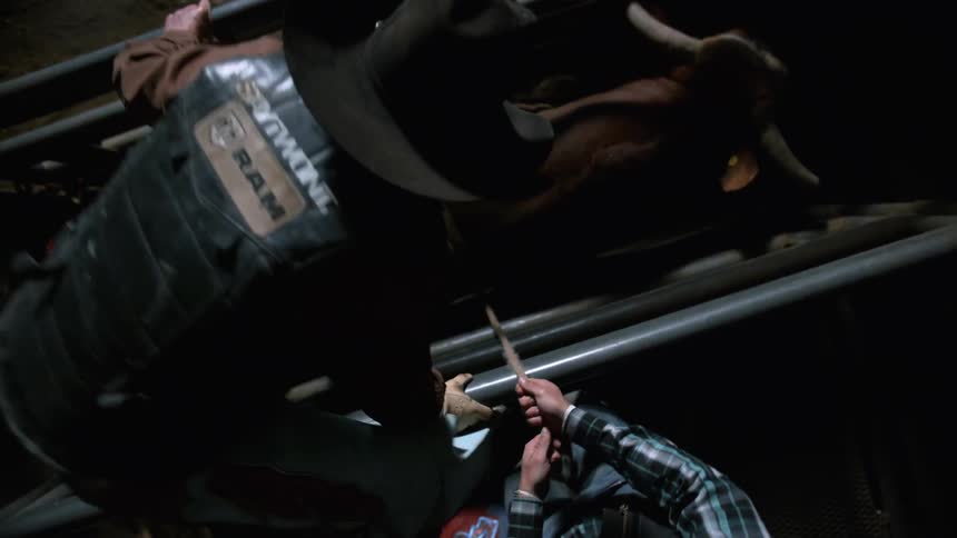 A man gets on a bull locked in a cage