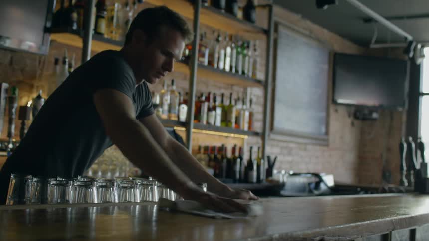 Bartender wiping up an area of his bar