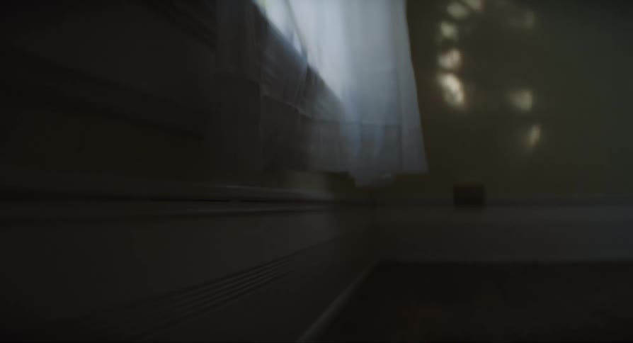 A curtain in front of an open window flutters in the wind