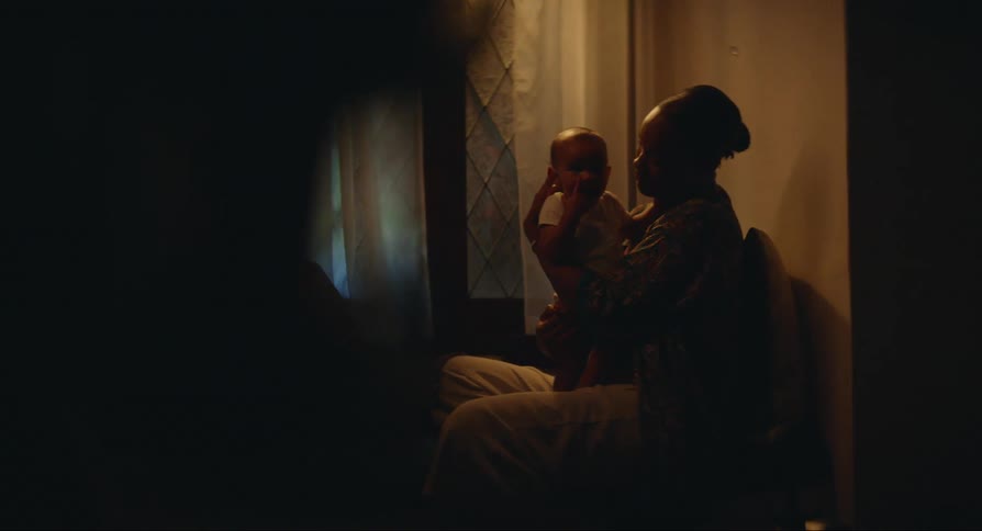 A woman sitting and giving a kiss on her babys cheek