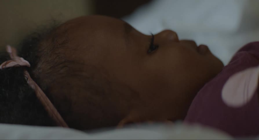 Black female baby lying down in a bed indoors during day time