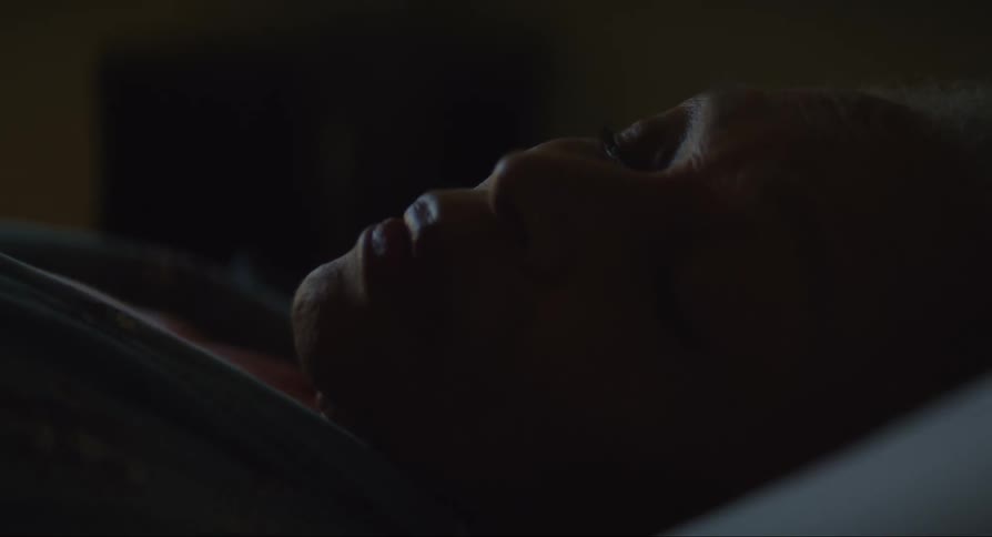 An elderly woman lays back in bed and closes her eyes a few times while attempting to sleep