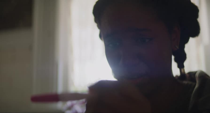 A young girl panics as she checks a pregnancy test