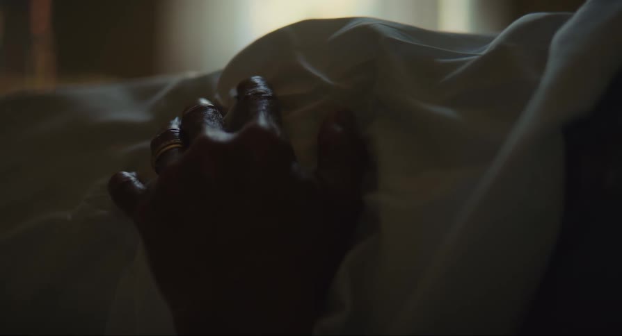 Hand rests on top of wrinkled white sheet
