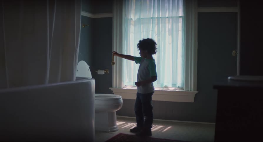 Boy in the bathroom throwing an object into the toilet