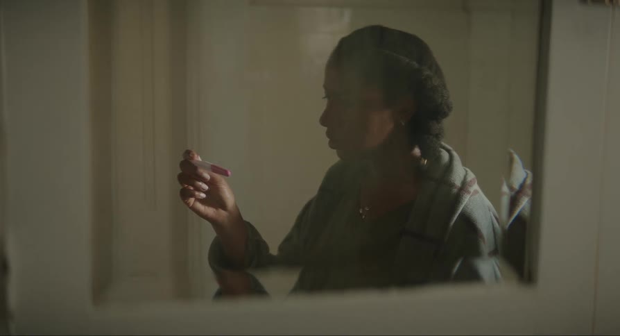 Bathroom mirror reflects young woman crying after she looks at pregnancy test results