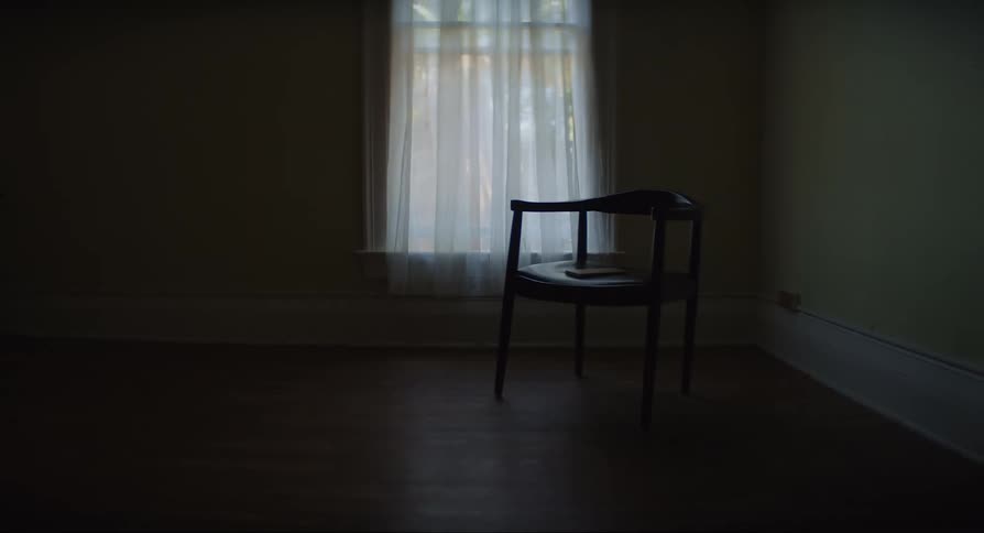 Solitary chair on the corner of a dimly lit room next to a window