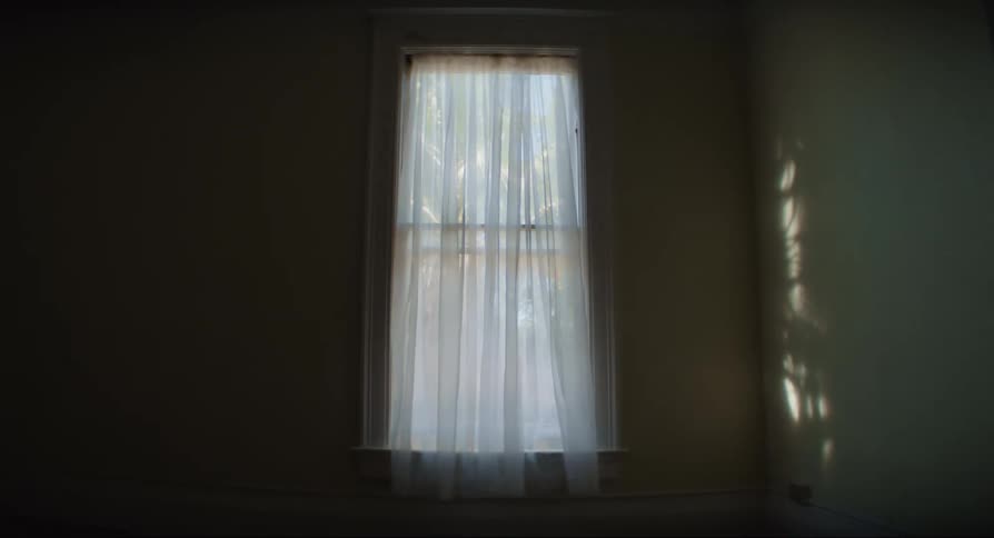 Wind blows window curtain changing the sunlight cast onto the wall