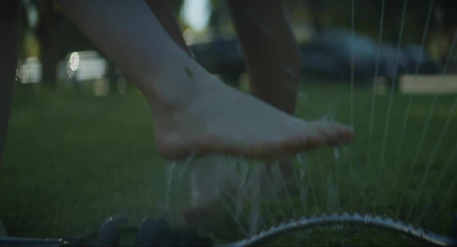 Two young girls washing their feet with a lawn sprinkler