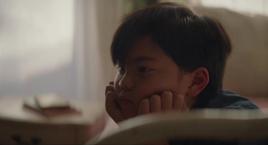 Boy lying on the bed with both hands supporting his chin
